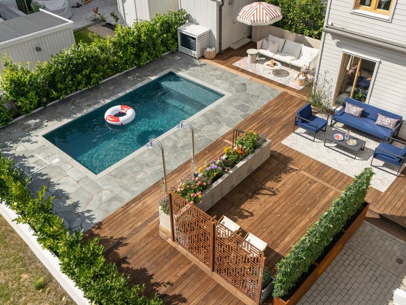 Nybyggd pool med natursten och träaltan på uteplats i Solna