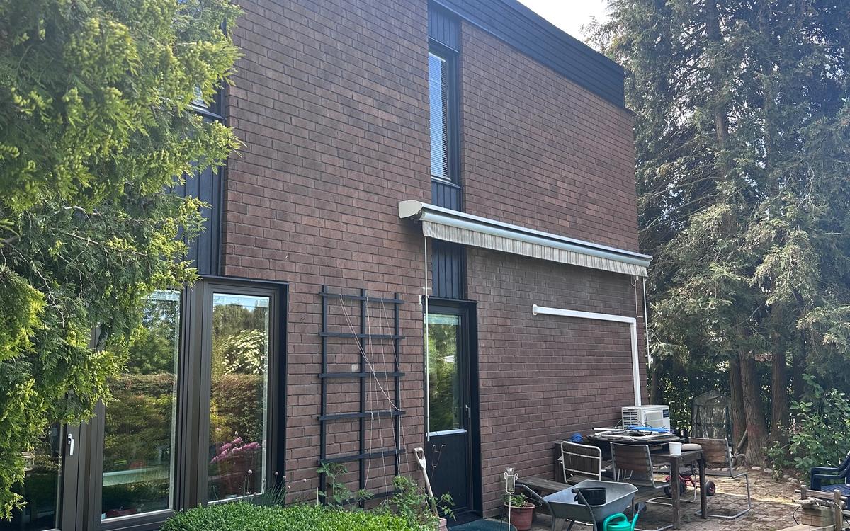 Nytt tvåkupigt lertegel i tegelröd kulör, vy från trädgården efter renovering