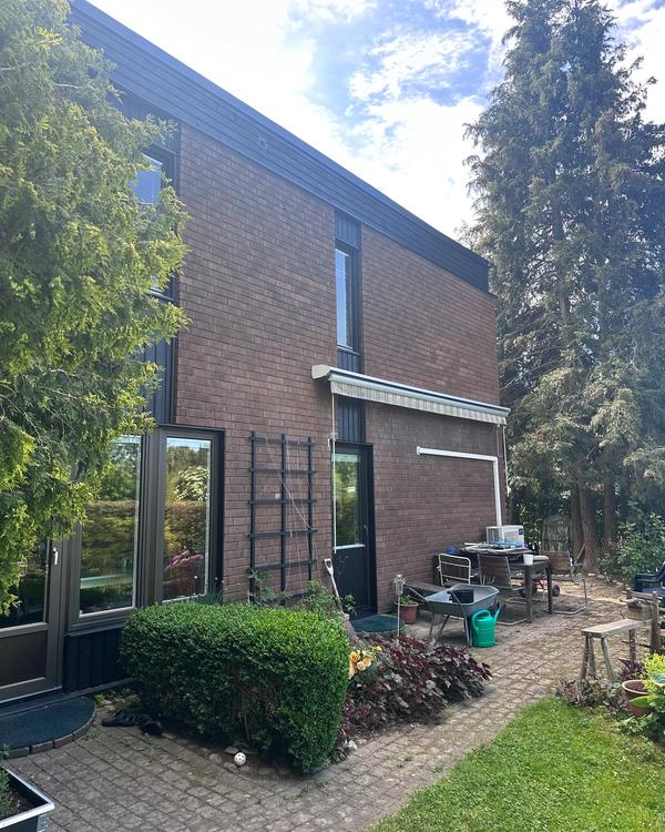 Nytt tvåkupigt lertegel i tegelröd kulör, vy från trädgården efter renovering