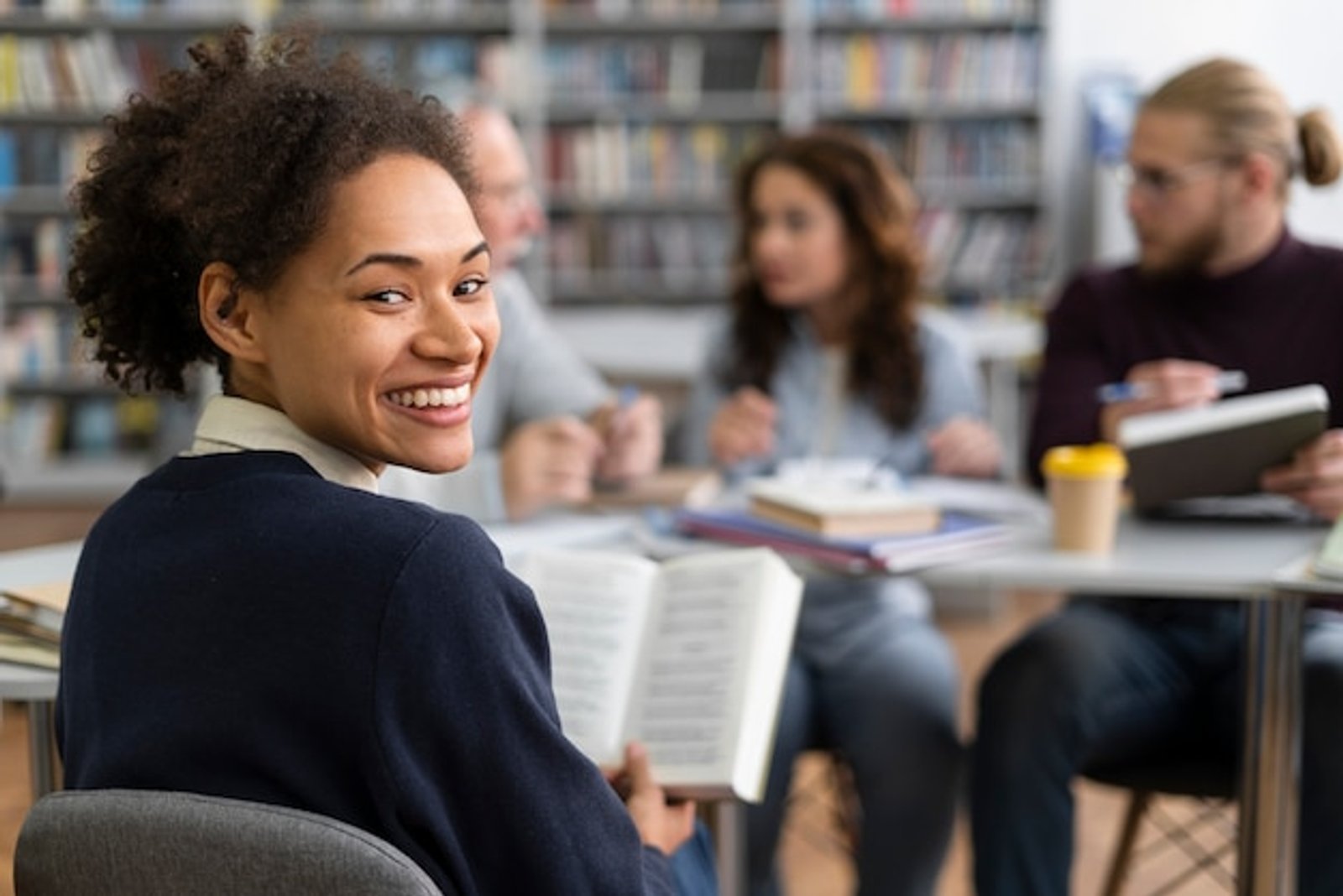 student in library reading and smiling