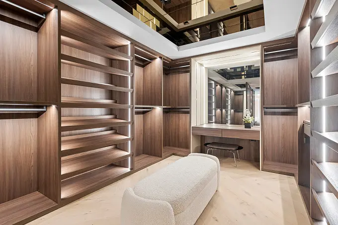 Modern wood walk-in closet featuring a vanity and dramatic mirrored ceiling.
