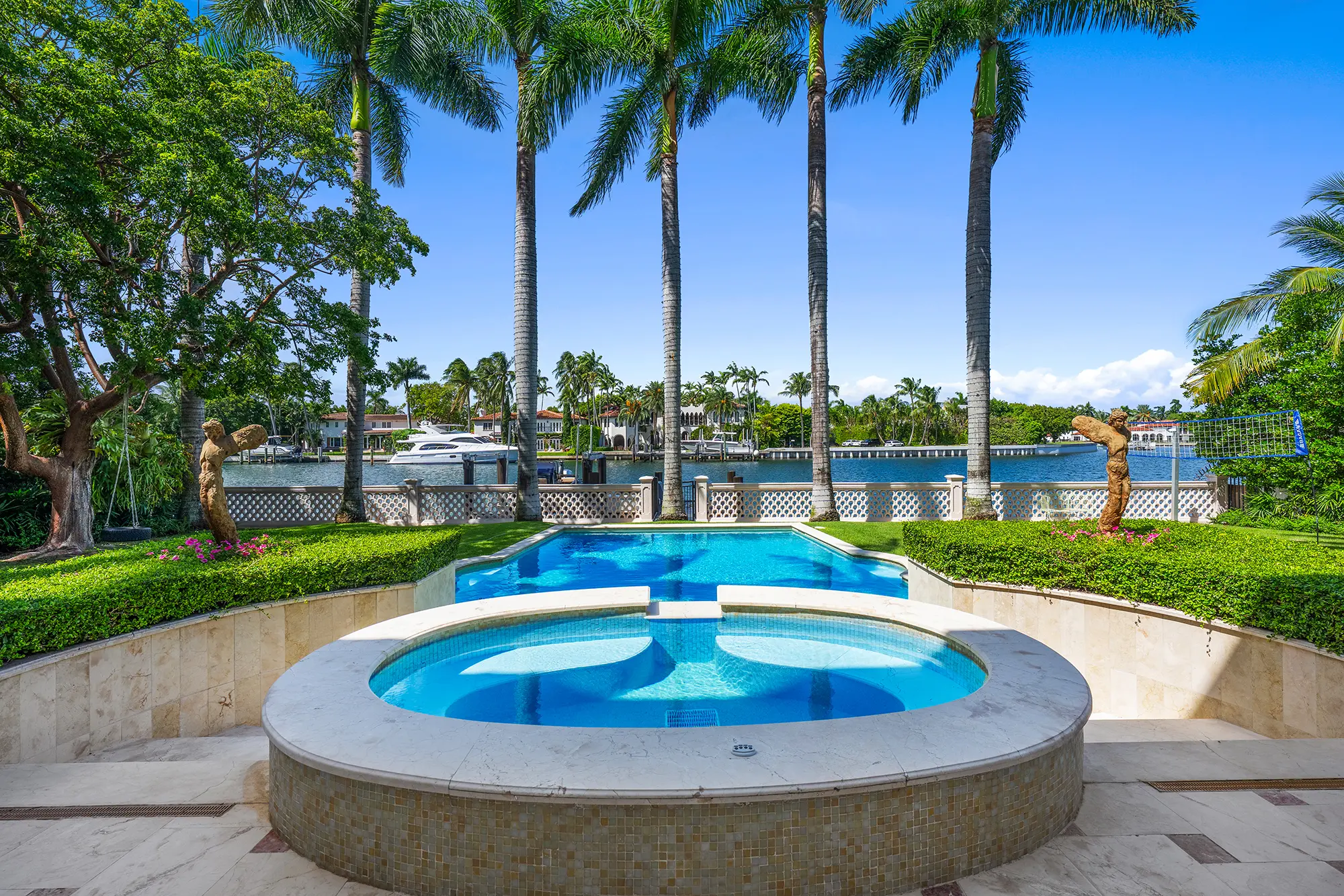 Luxury waterfront pool and spa with tropical landscaping.