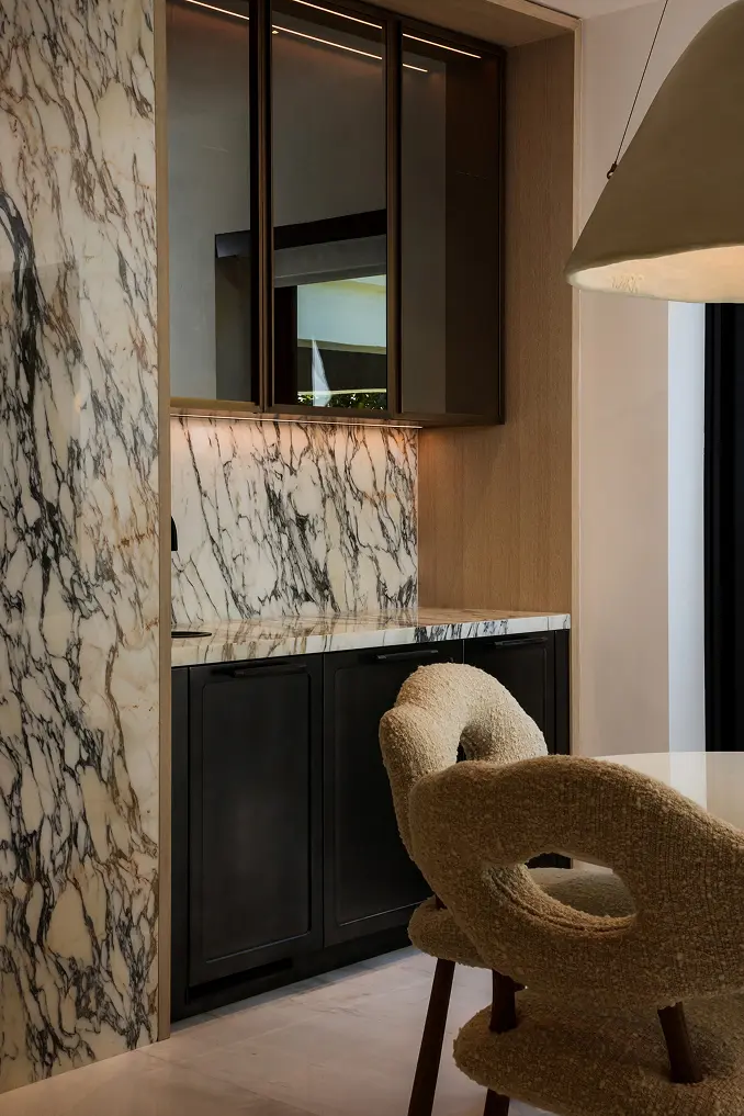 Modern black glass display cabinet set against a dramatic black-and-white marble feature wall.