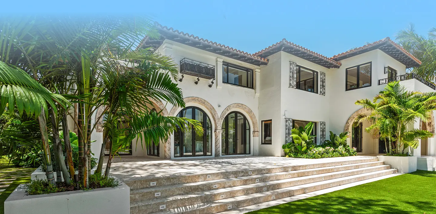 Spanish Mediterranean estate with white arched poolside pavilion, vibrant blue pool, and lush tropical gardens in Miami