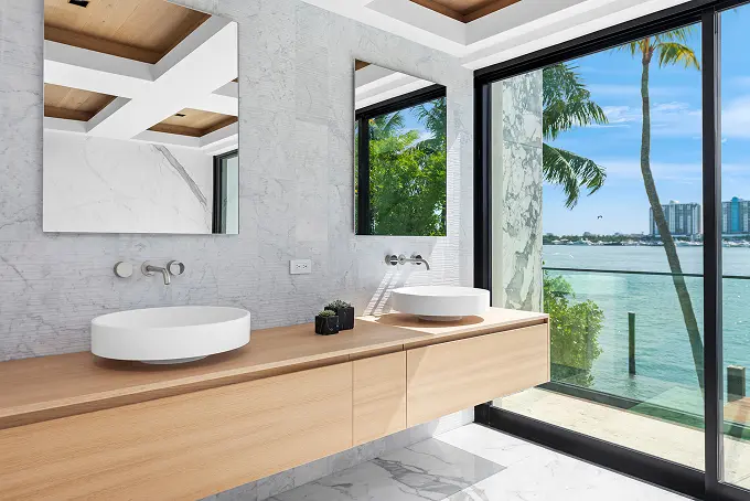 Spacious bathroom with a wood inlay ceiling and a large glass window overlooking the bay.