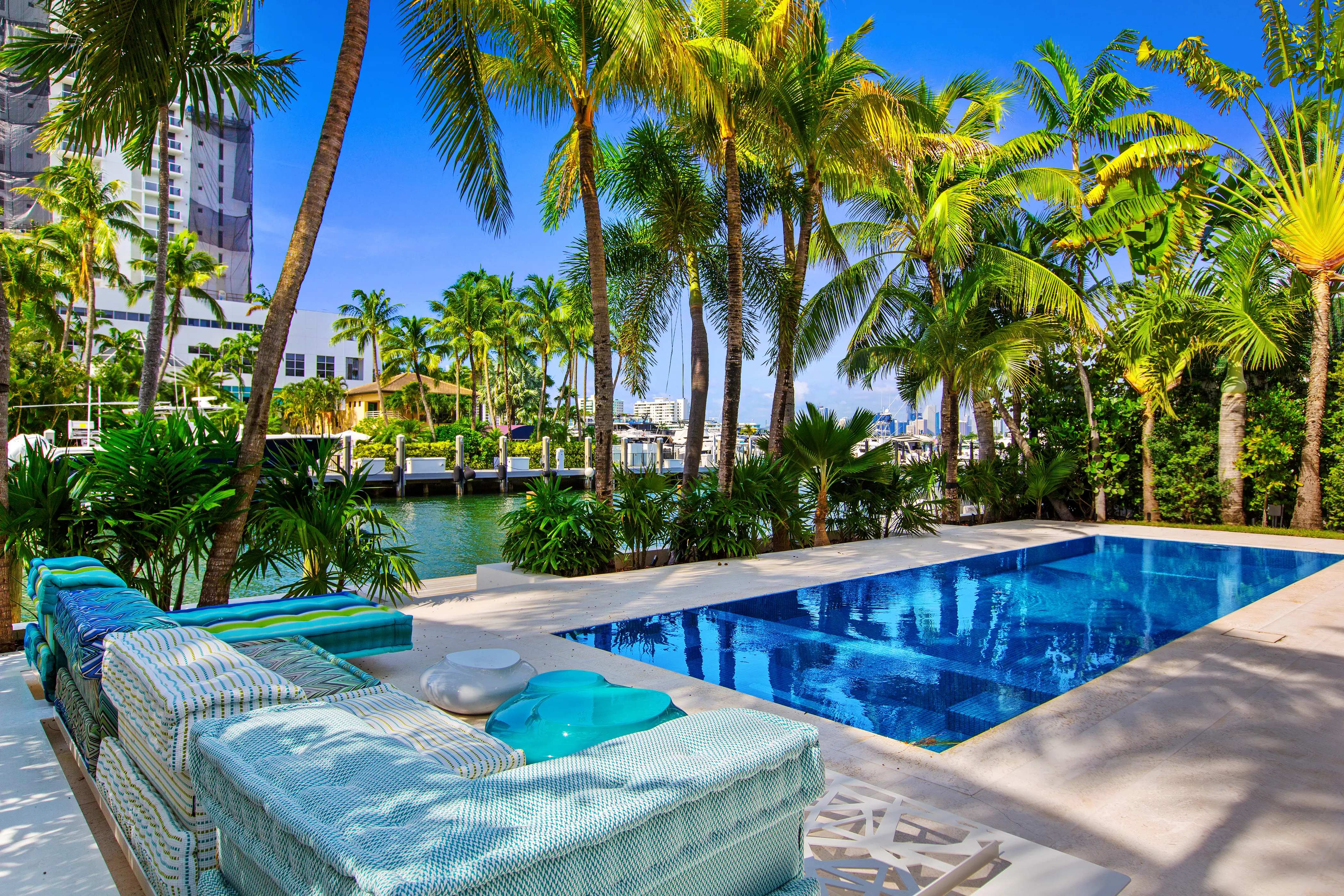 Luxury outdoor living area in Miami Beach featuring a private swimming pool, integrated spa, expansive pool deck, and lush tropical landscaping.