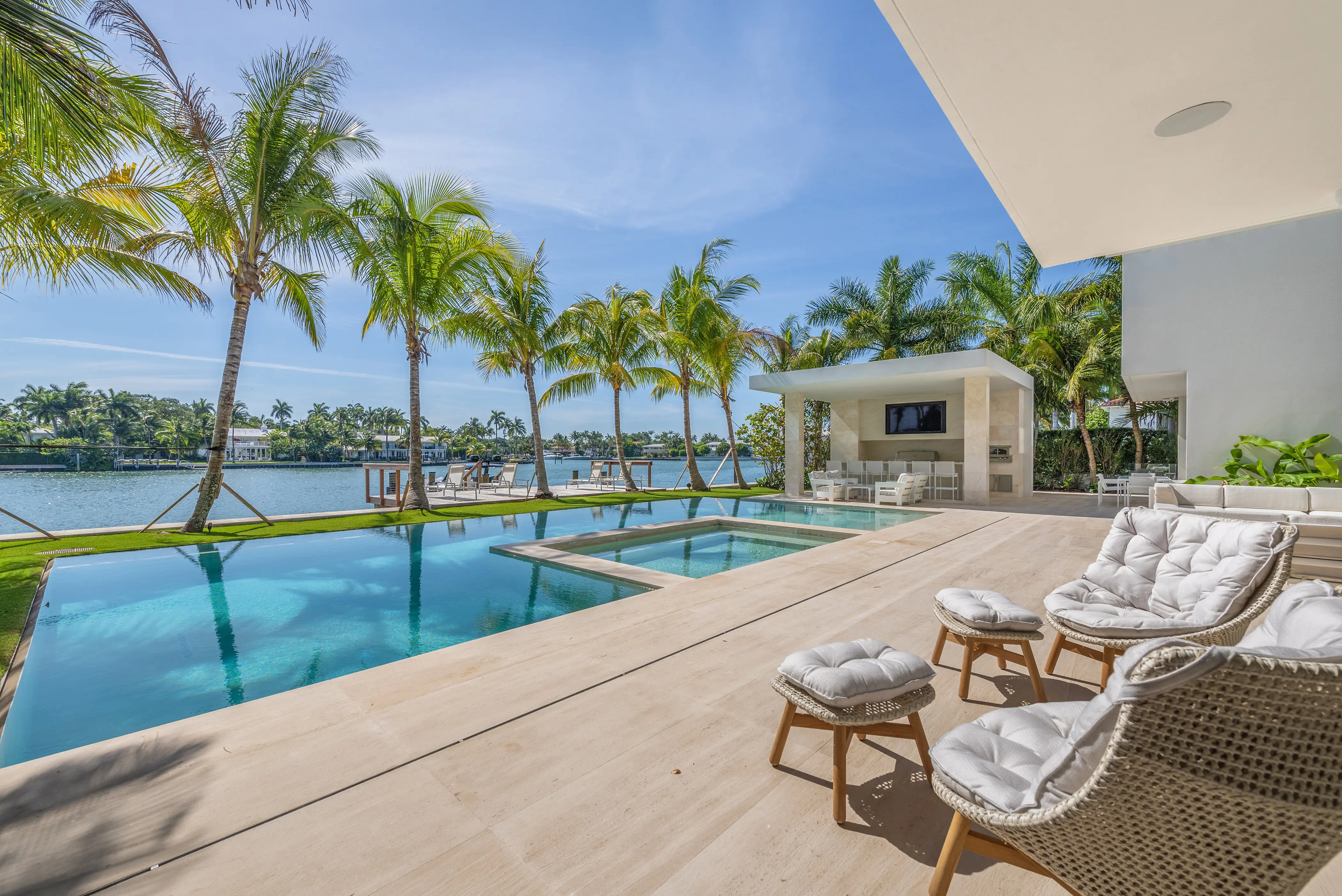 Patio view overlooking the pool, hot tub, palm trees, and the lake beyond.