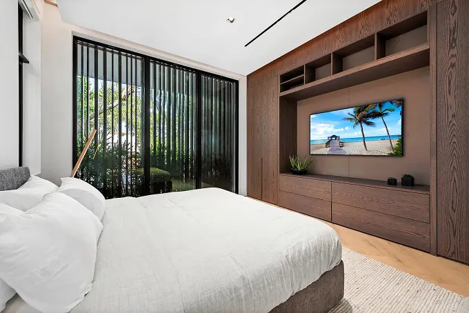 Spacious guest bedroom with tall ceilings and a built-in mahogany entertainment console.