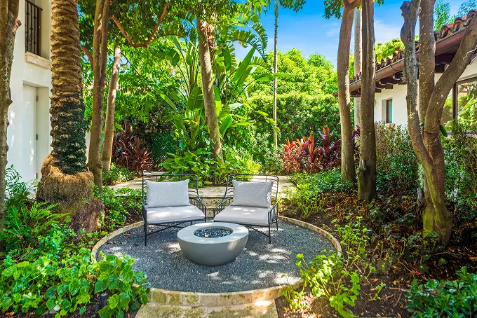 Cozy outdoor fire pit lounge tucked among the palms in the garden.