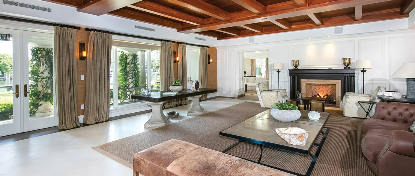 Spacious living room with a statement fireplace, elegant sconces, and soaring ceilings.