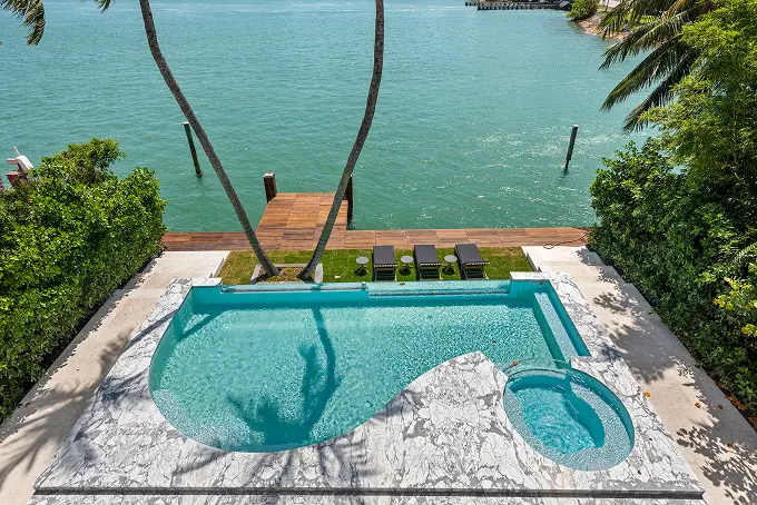 Pool overlooking the bay with a private dock just beyond the water's edge.