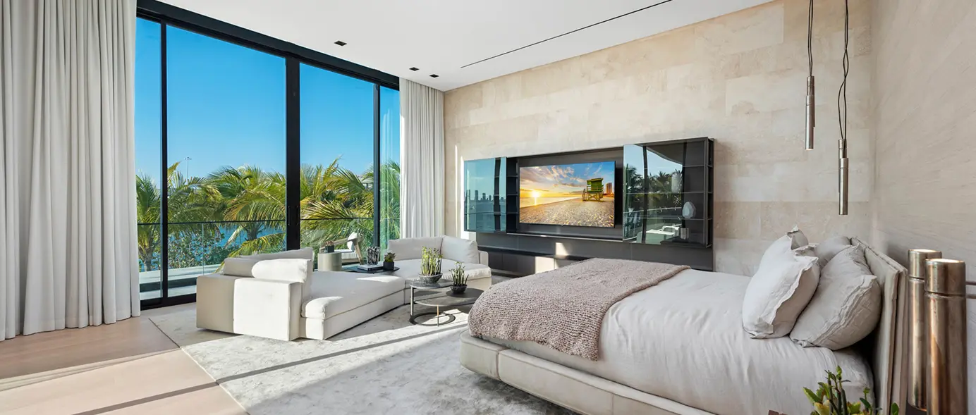 Bedroom with modern stone walls, wood floors, and tall ceilings overlooking the bay.