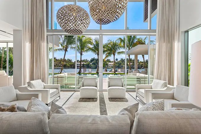 Backyard view from the living room through expansive two-story floor-to-ceiling windows.