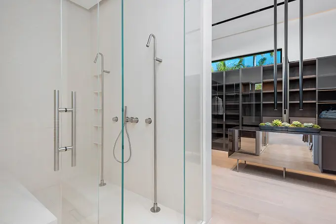 Dual-head standing shower with a view into the spacious walk-in closet beyond.