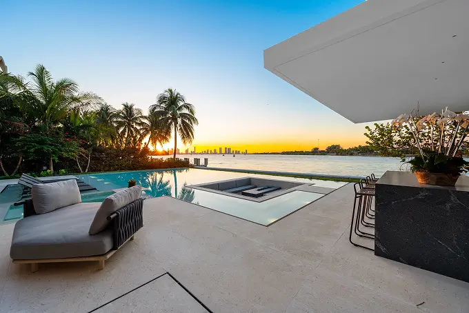 Infinity pool by the lake with an adjoining bar, captured at sunset.