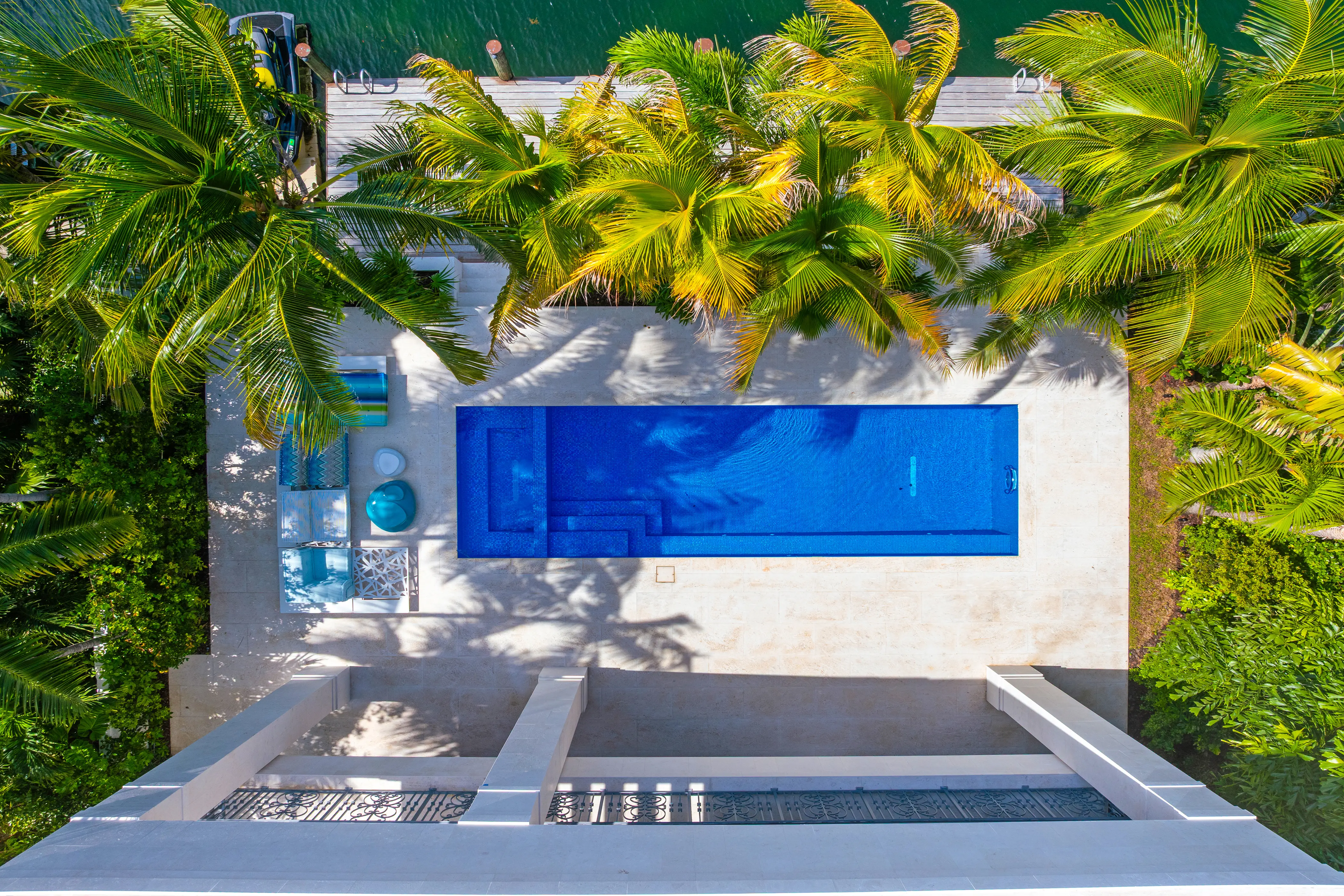 Aerial view of a luxury Miami Beach residence showcasing a rectangular swimming pool, expansive outdoor living areas, and dense tropical landscaping.