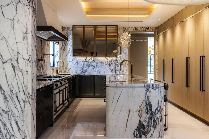 Soaring kitchen with dramatic black-and-white marble surfaces and double-height ceilings.
