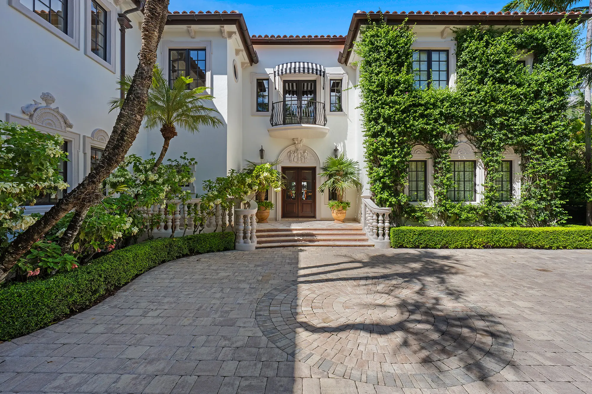 Luxury Mediterranean home entrance with courtyard and tropical landscaping.