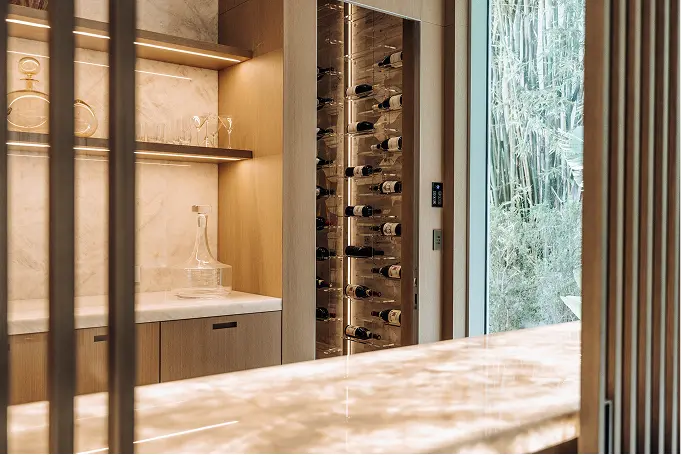 Modern kitchen featuring a backlit marble island and a striking wine display rack.