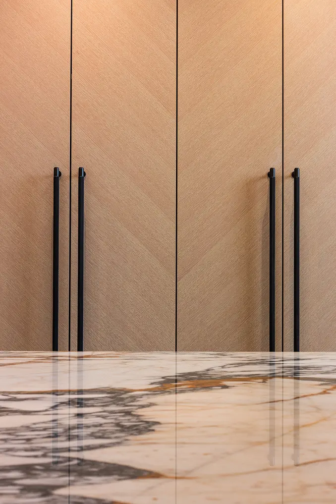 Sleek wooden cabinetry against a black-veined marble countertop in a sophisticated Miami kitchen.