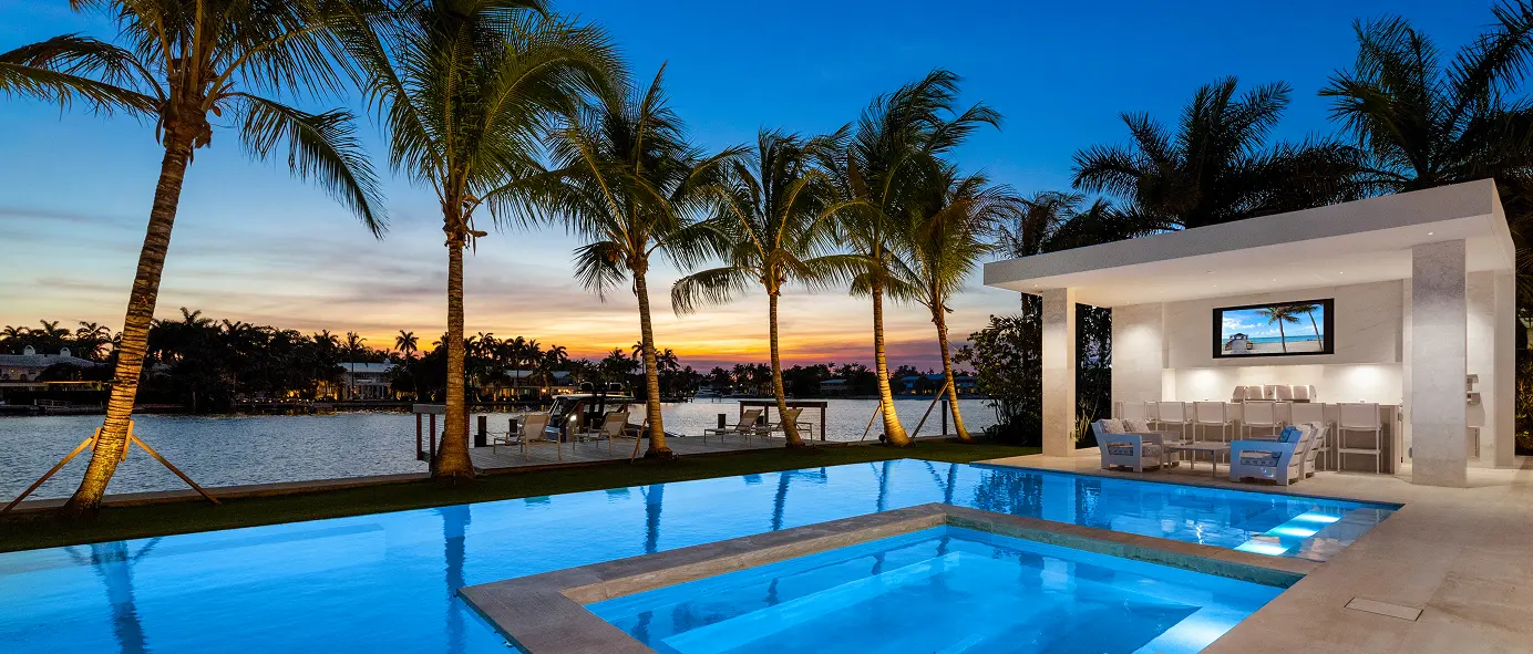Pool and outdoor bar illuminated at sunset, overlooking the tranquil lake.