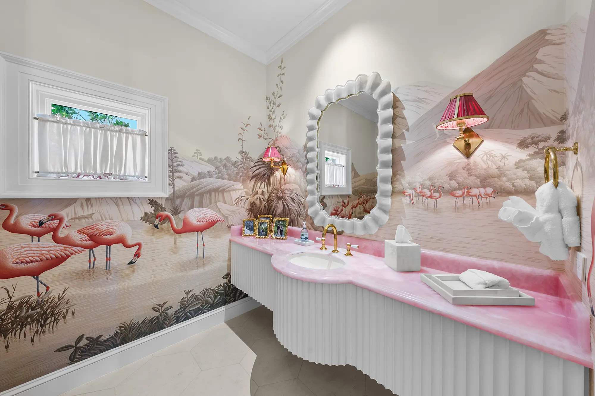 Luxury powder room with flamingo mural, pink vanity and brass fixtures.
