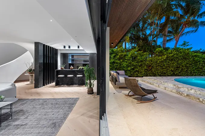 Poolside patio seamlessly adjoining the living room and bar for indoor-outdoor entertaining.