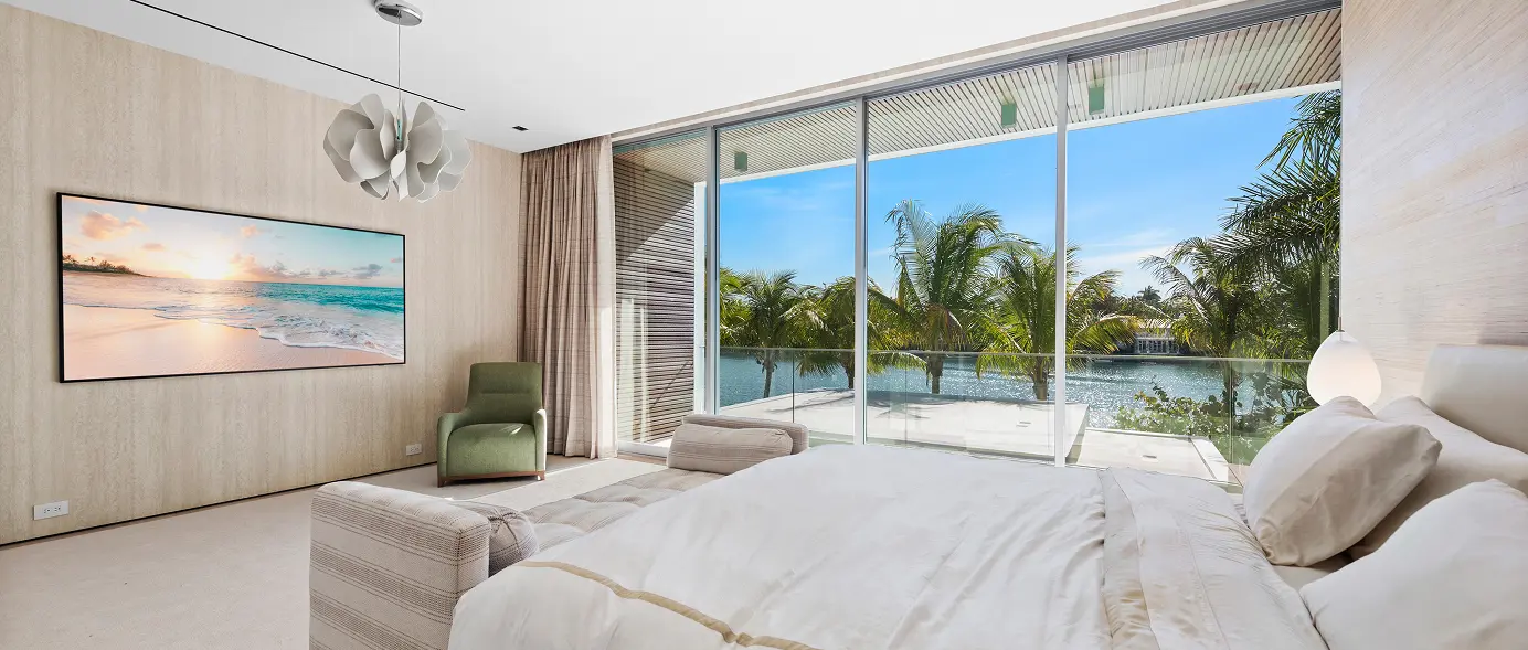 Bedroom with tall ceilings and views overlooking the palm-lined lake.