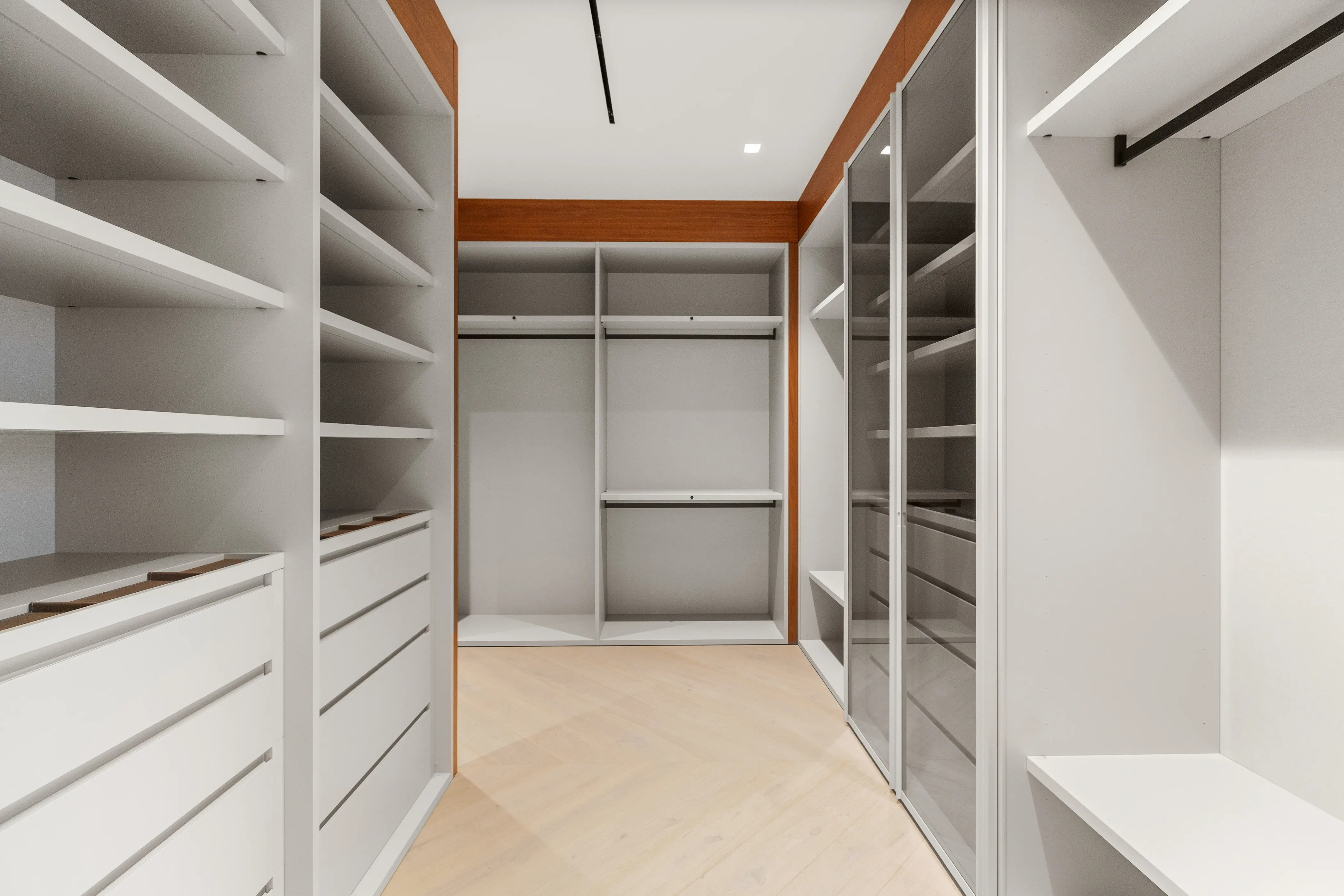 Spacious custom walk-in closet featuring floor-to-ceiling built-in cabinetry, integrated shelving, drawers, and refined contemporary millwork.