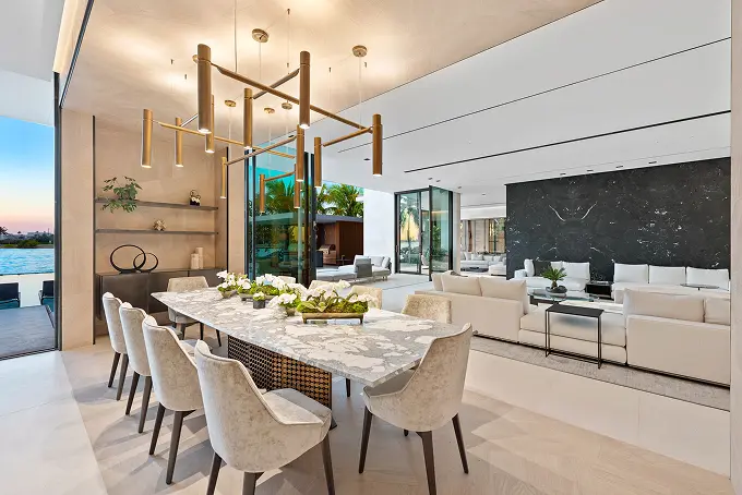 Open-plan dining and living room with tall ceilings, set poolside.