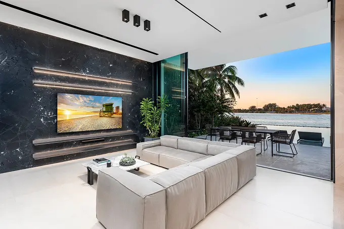 Convertible indoor-outdoor patio living room with a large TV, overlooking the bay.