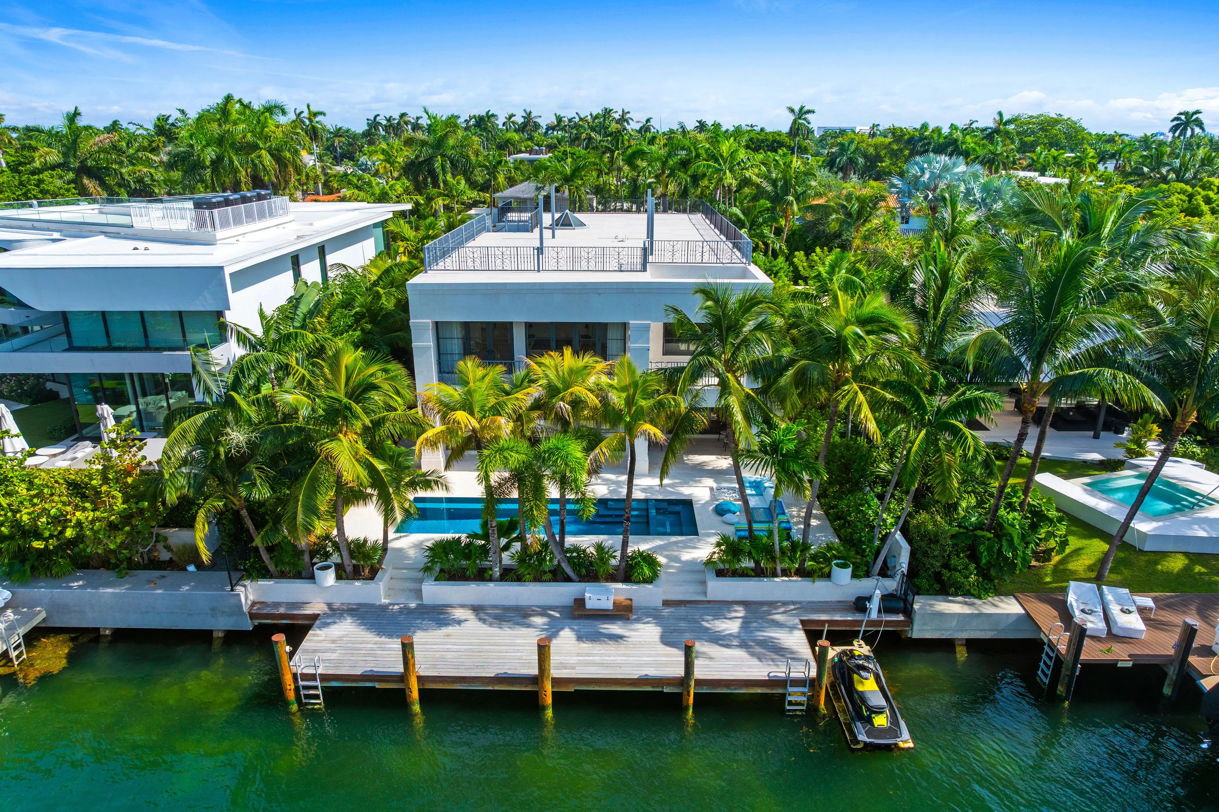 Aerial view of a contemporary waterfront residence in Miami Beach surrounded by tropical landscaping with private dock access and modern outdoor living spaces.