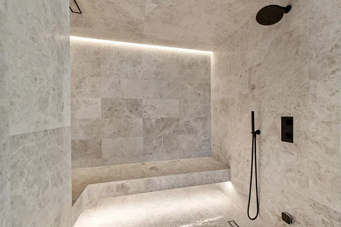 Expansive marble bathroom with a built-in bench and soft ambient lighting throughout.