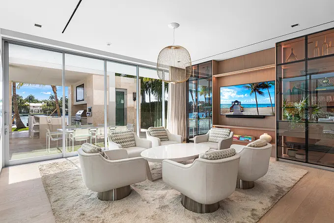Naturally lit entertainment room with floor-to-ceiling glass doors opening to the outdoors.