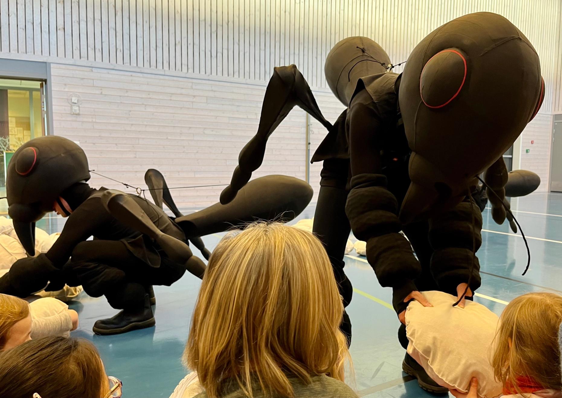 Dansere utkledde som maur spiller forestilling, i møte med barn