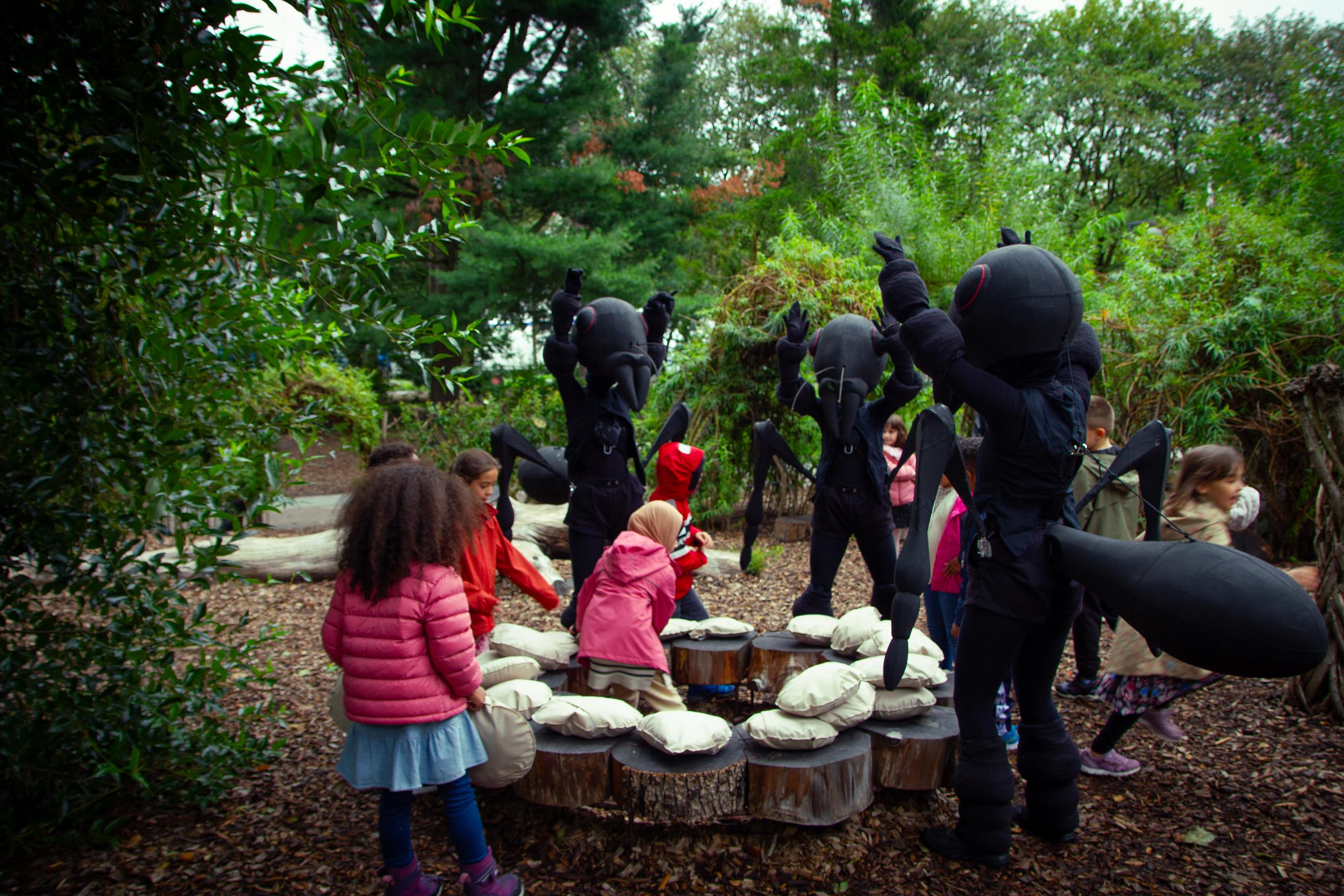 Tre dansere utkledd som maur sammen med en 1. klasse i botanisk hage