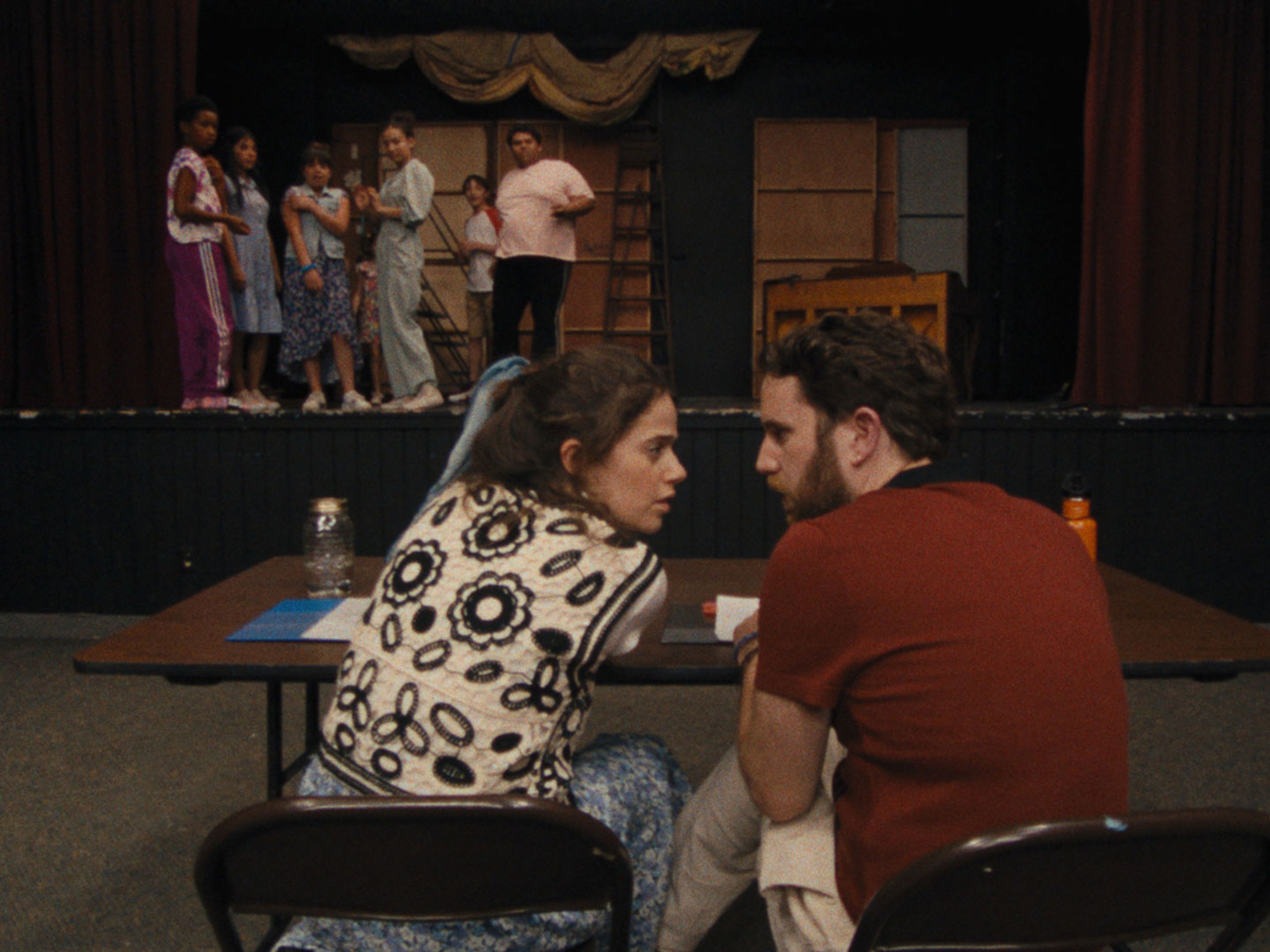 at theater man and woman talking while cast is on stage