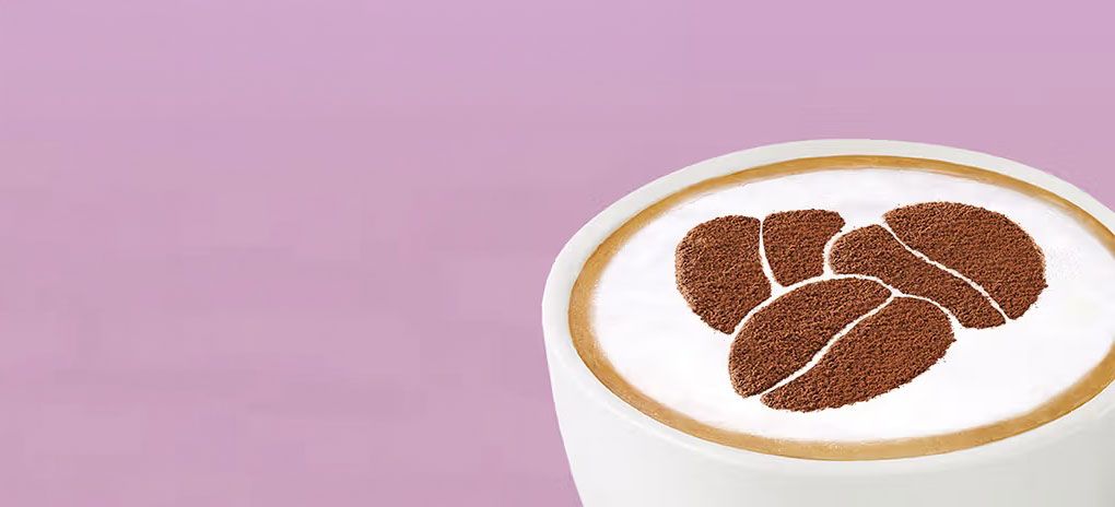 A picture of a cup of cappuccino on a pink background.