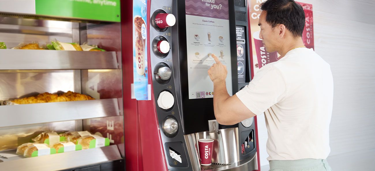 A man is ordering a coffee at a Costa Express machine