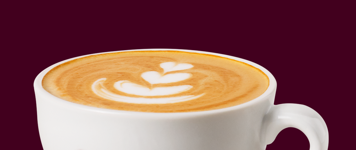 Taza blanca de cappuccino con arte latte de corazón en la espuma