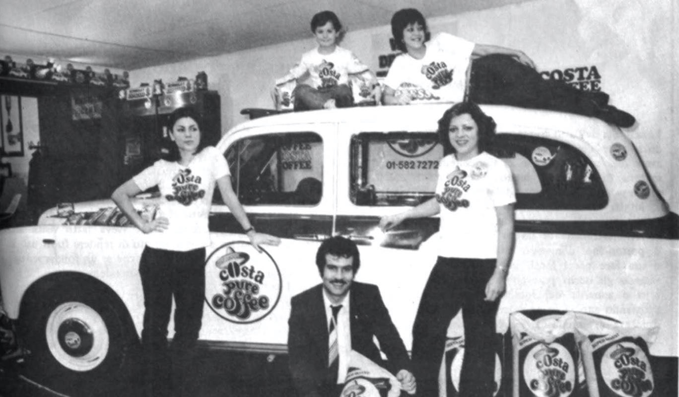 Antiguo anuncio de Costa Coffee: grupo junto a taxi clásico, sacos de café y 01-582 7272