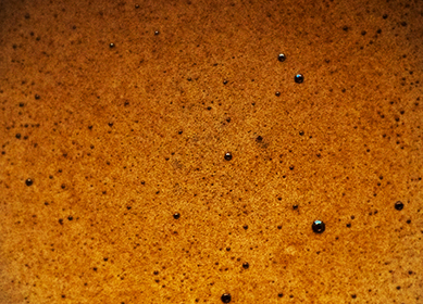 Primer plano de café espresso marrón con espuma y burbujas en la superficie