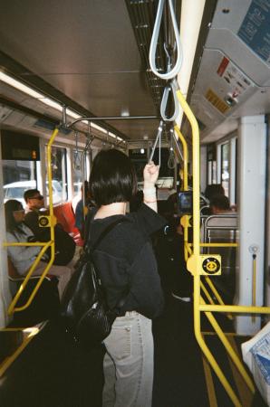 Passenger holding an overhead strap while standing inside a crowded city bus.