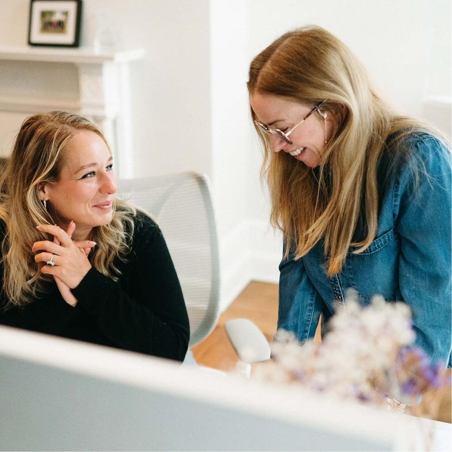 Two colleagues laughing together at a desk
