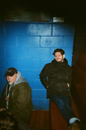 Man sitting on a bench, leaning against a blue concrete block wall