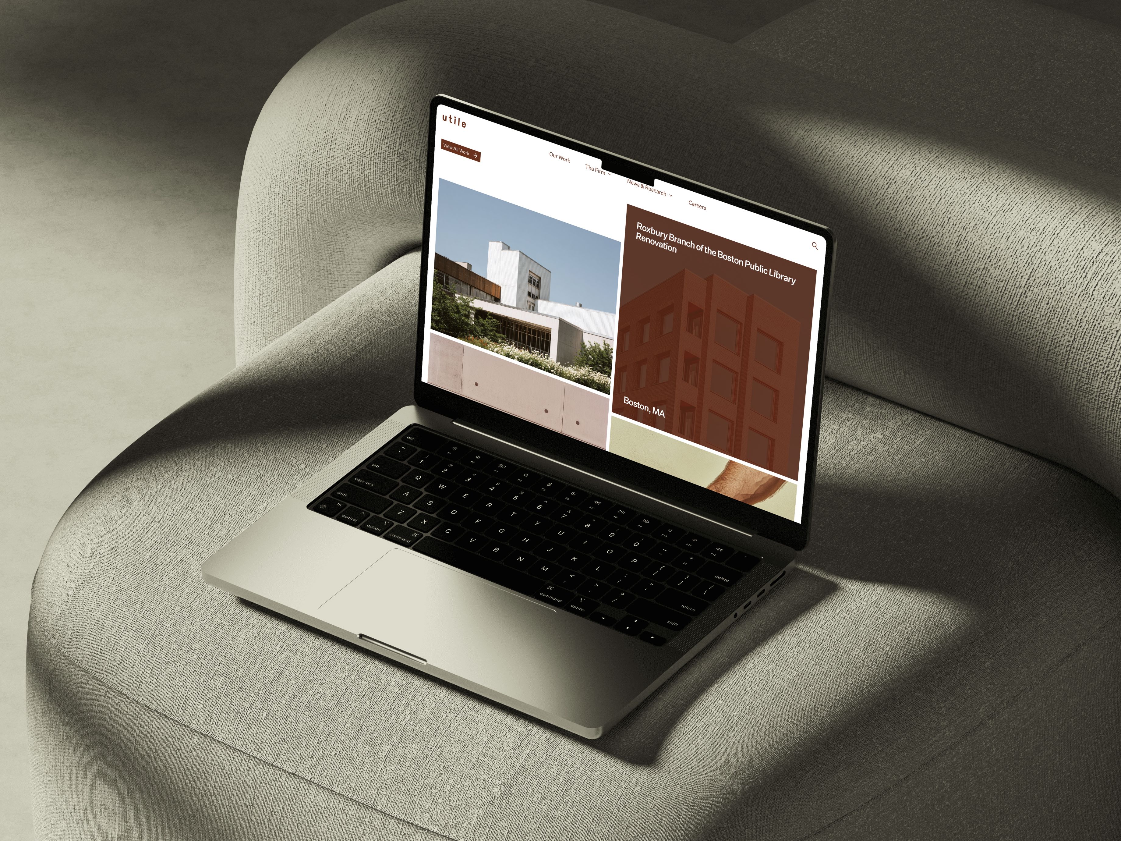 A laptop on a chair cushion displaying the Utile Design website