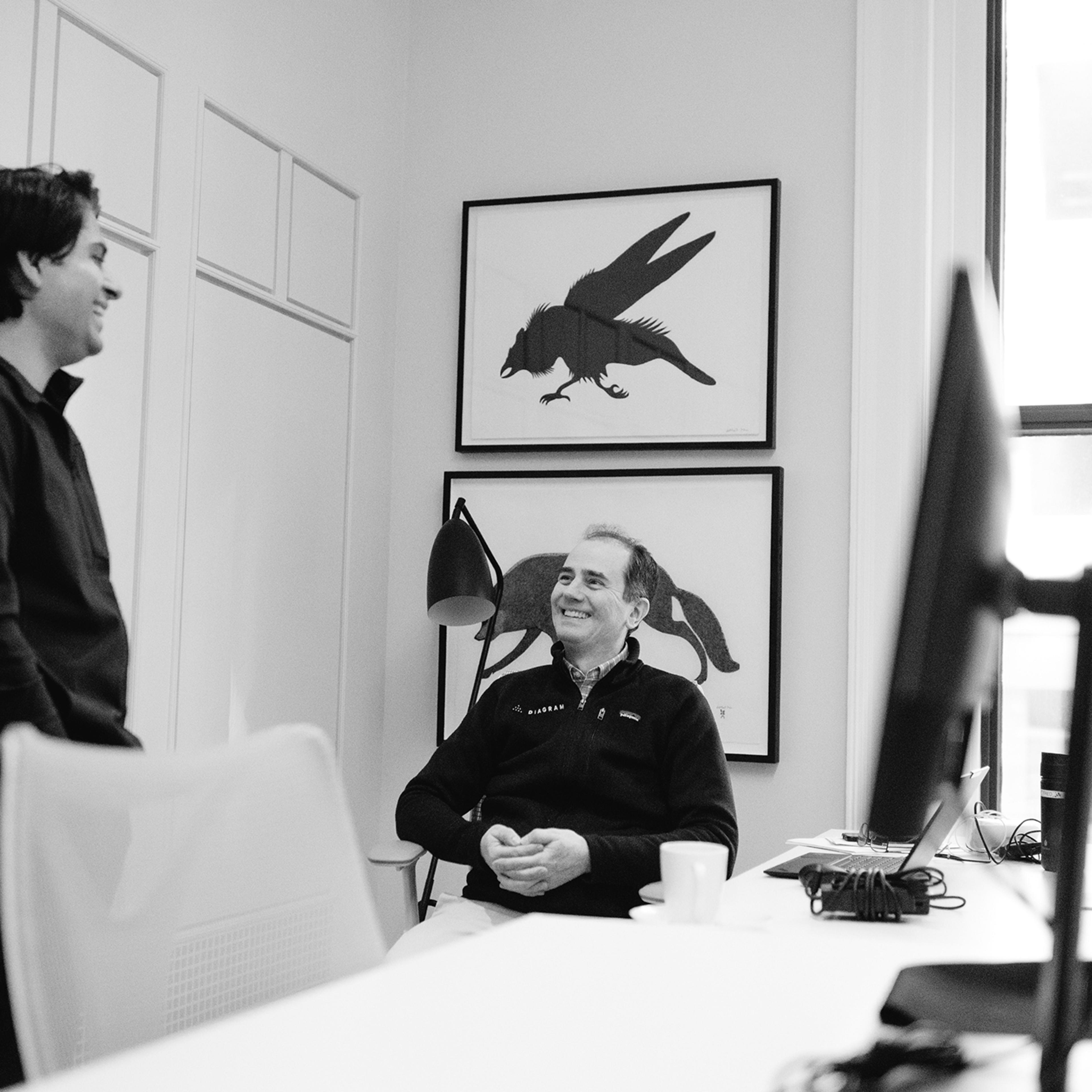 Black and white image of two coworkers smiling and laughing