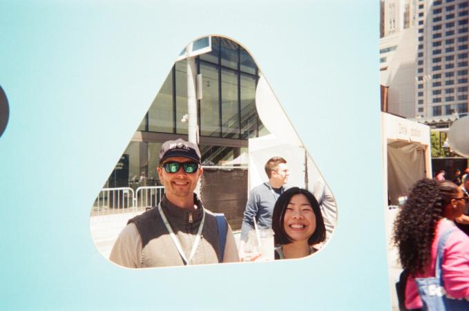 Two people smiling at the camera, framed by a rounded triangle cutout