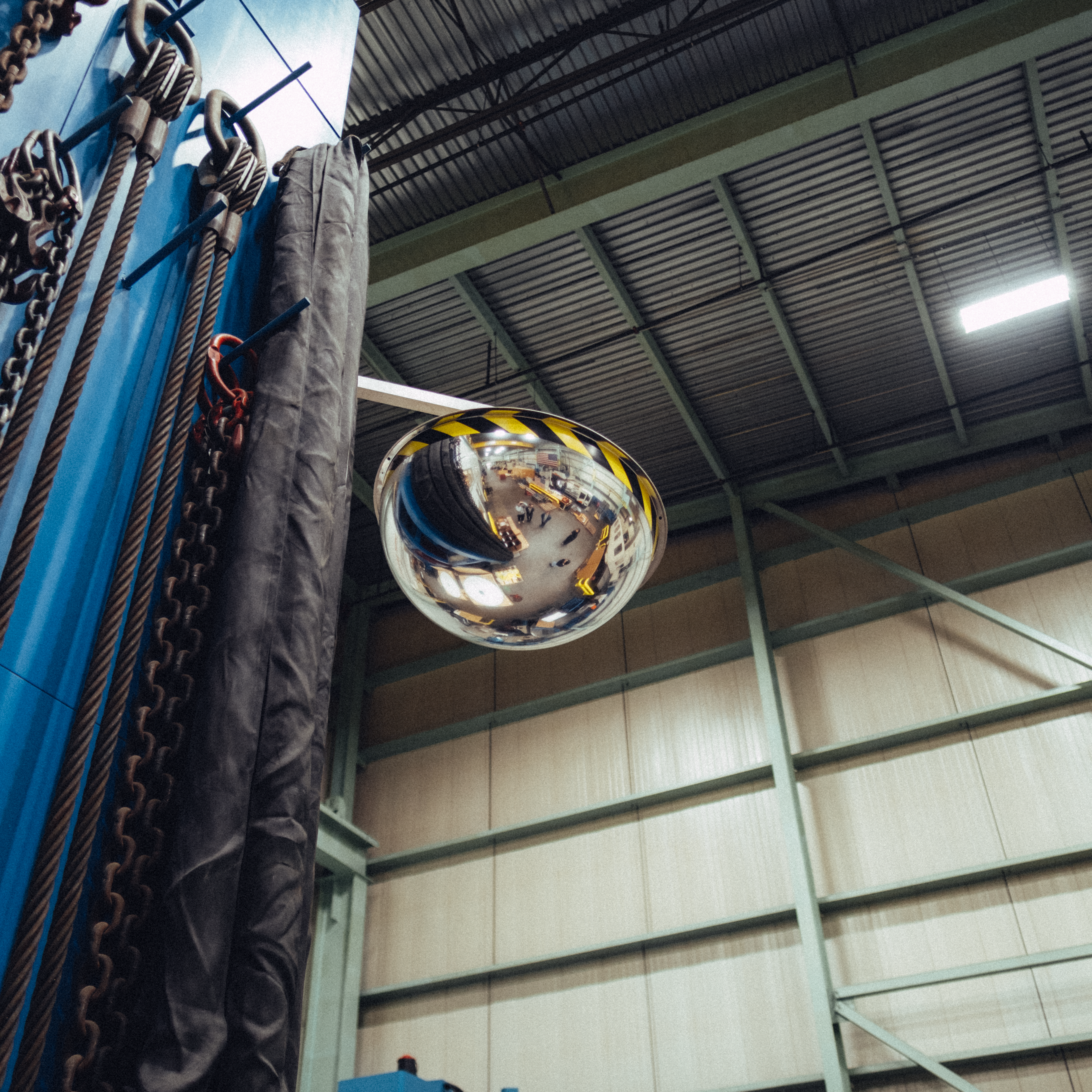 A mirrored convex dome reflecting an industrial warehouse setting