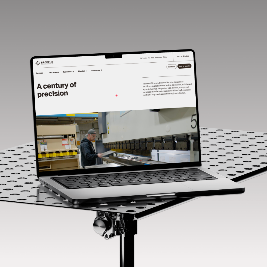 The Brodeur Machine site on a laptop, resting on a perforated steel work table
